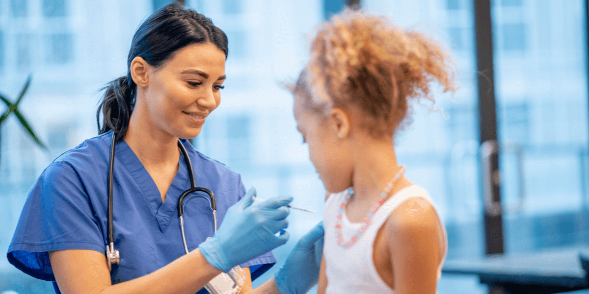 Female nurse administering a shot to a young girl in a doctor's office. 